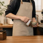 Barista mặc tạp dề cafe màu trung tính trong quầy pha chế hiện đại